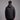 A man viewed from the back wearing a black hooded puffer jacket against a plain gray studio background.